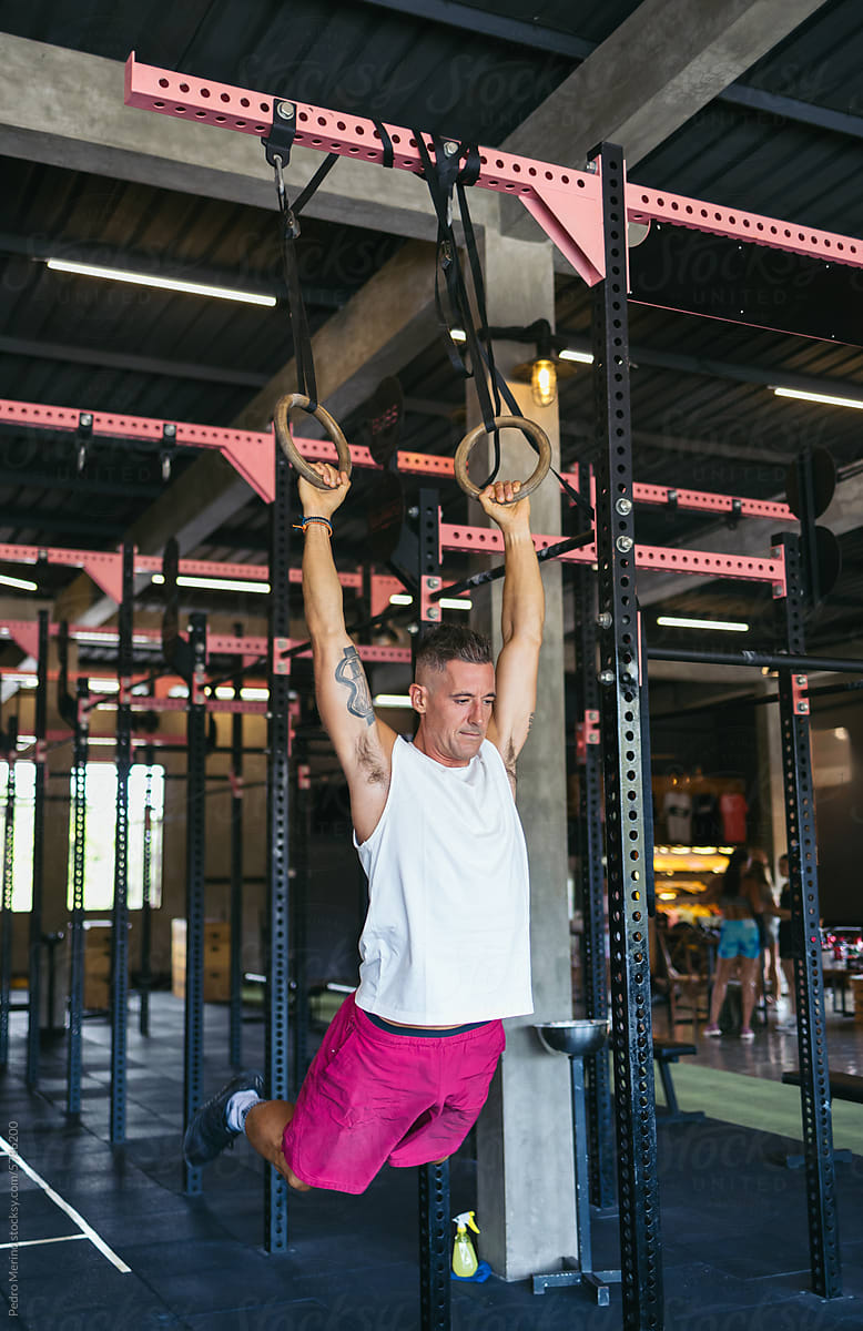 man exercising in the gym using rings