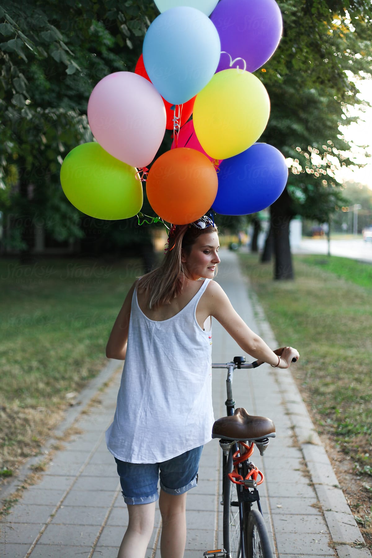 Woman walking with bicycle and colorful ballons