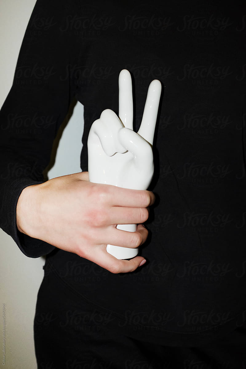 Hand holding a porcelain statue showing peace sign with flashlight