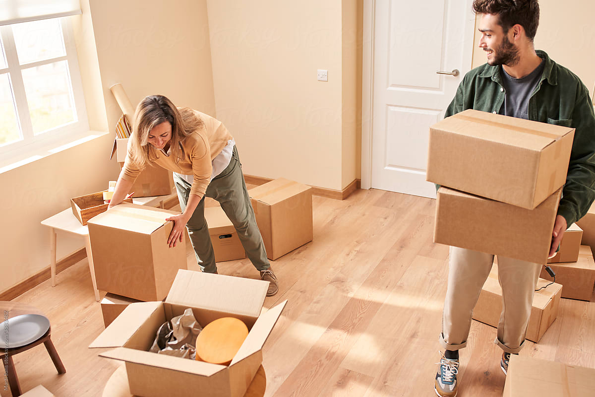 Young couple carrying carton boxes in new apartment