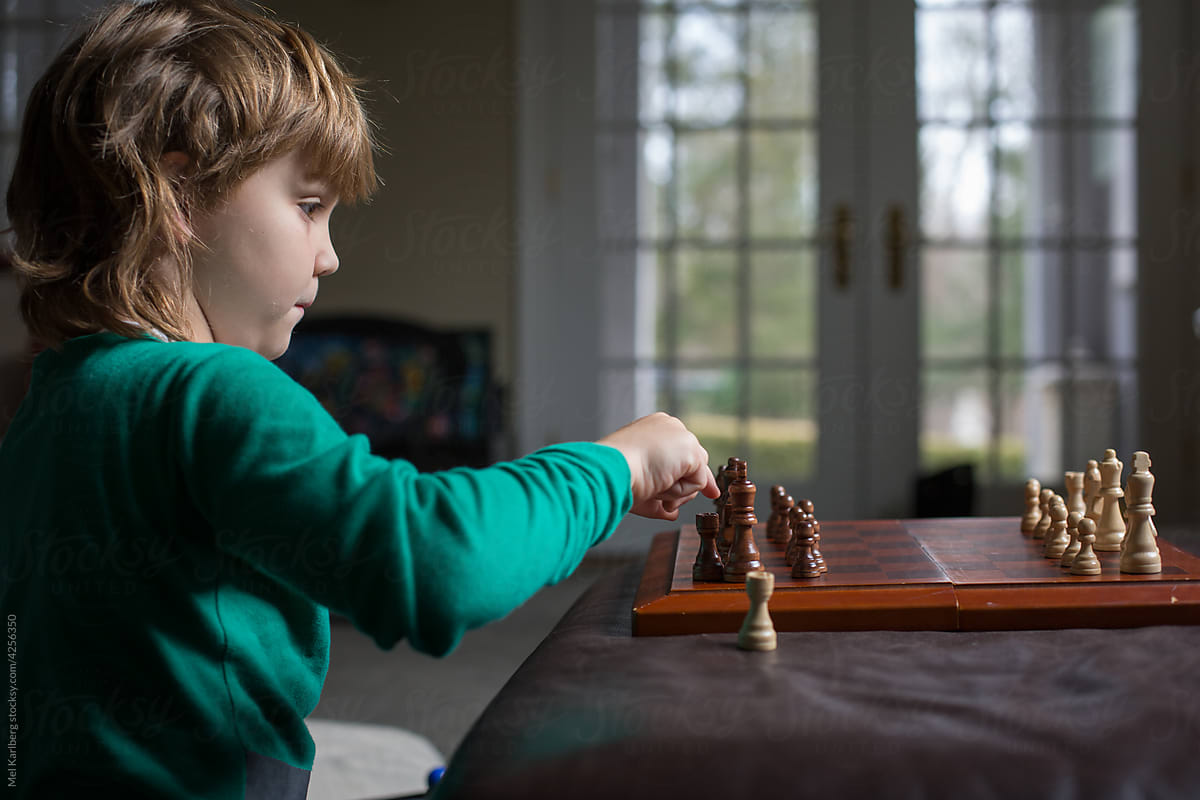 Boy\'s profile as he studies chess board