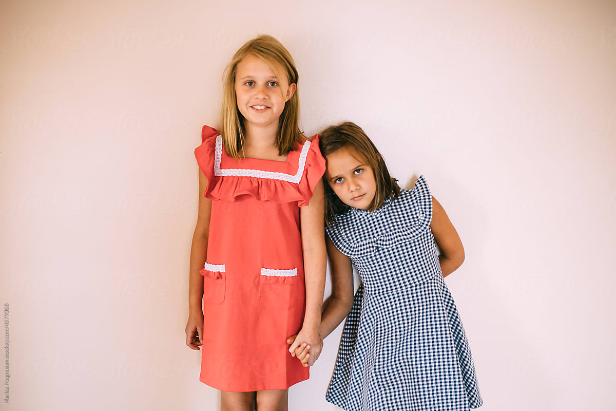 Sisters in dresses holding hands.