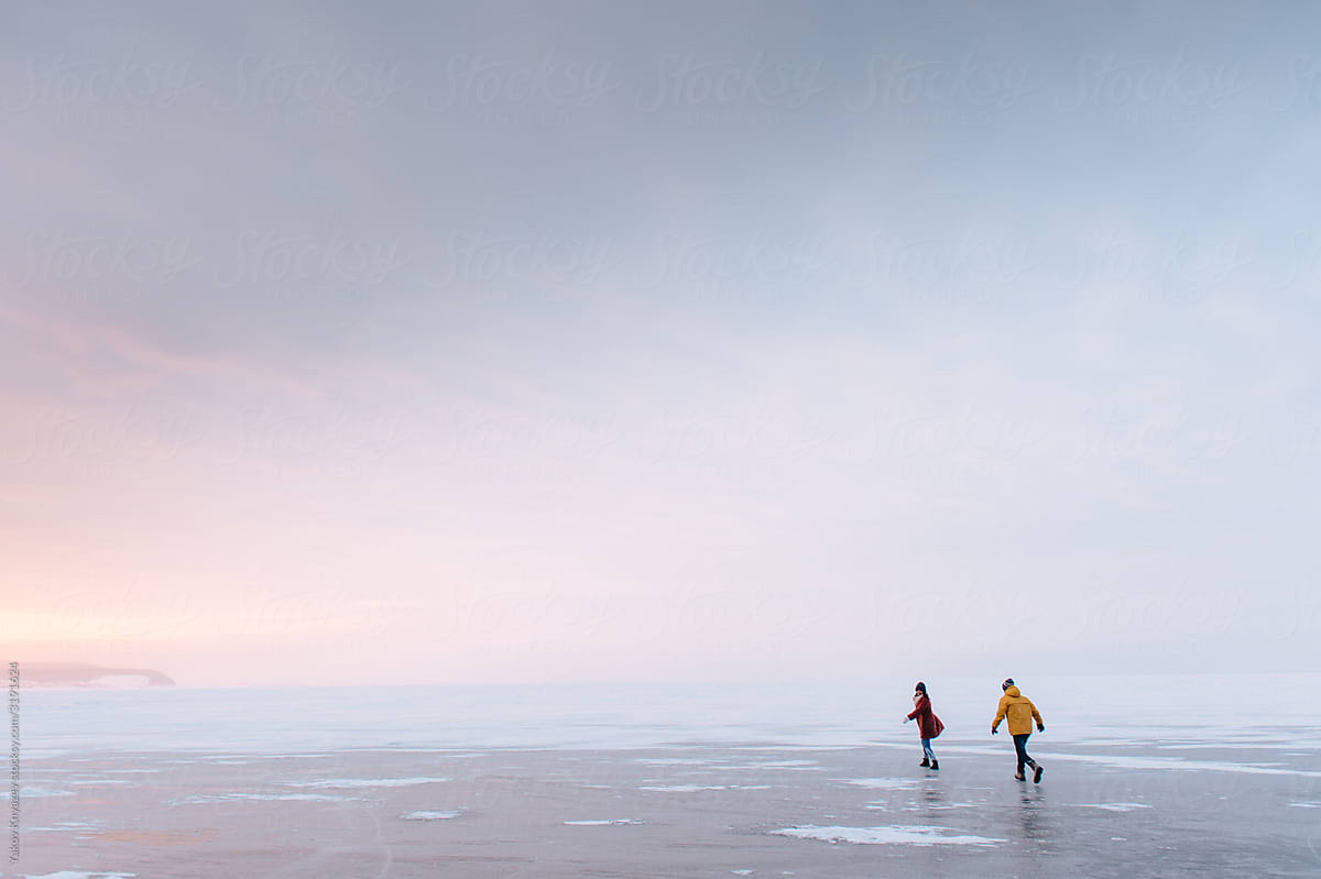 Couple running around on the ice at the sunset