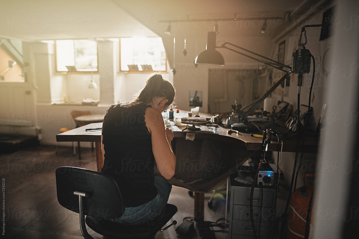 Female artisan sitting at a workbench making jewelry