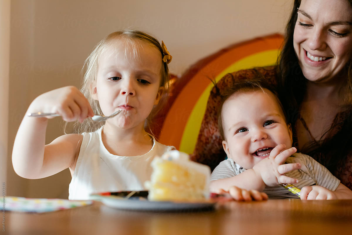 Girl Sitting with Mom and Brother Eating Birthday Cake