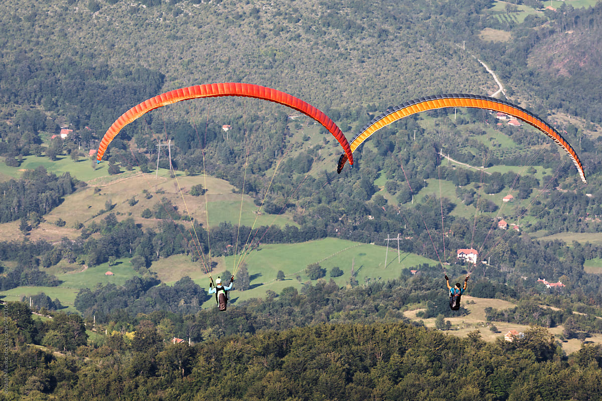 Two paragliders in the air over mountains