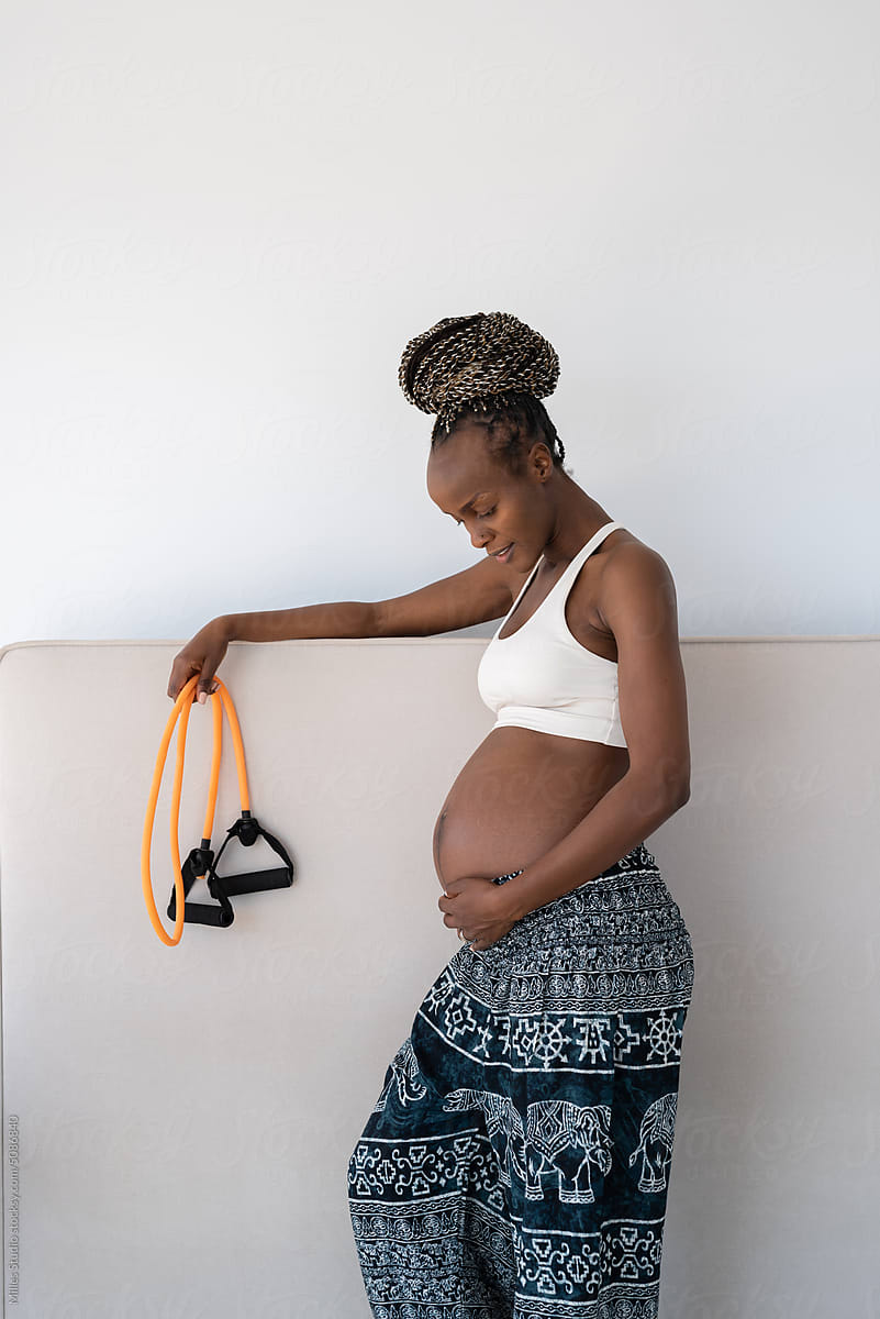 Happy pregnant black woman holding resistance band