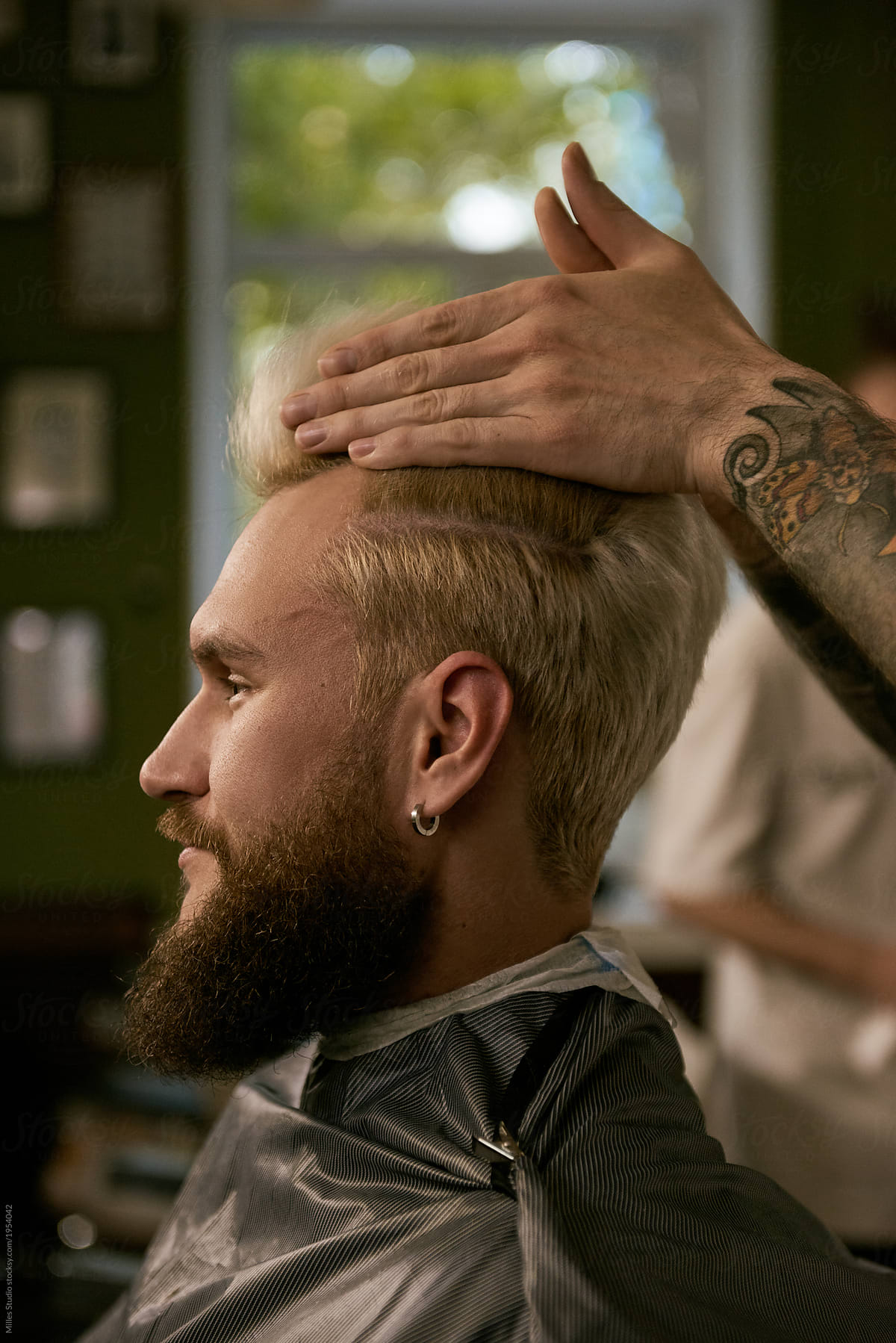 Bearded man having hairstyling in barbershop