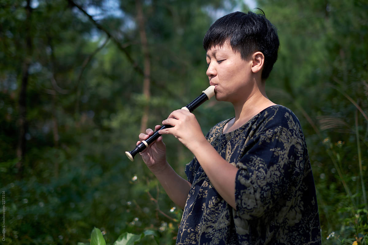 Asian woman playing the flute in the countryside field during the harvest season