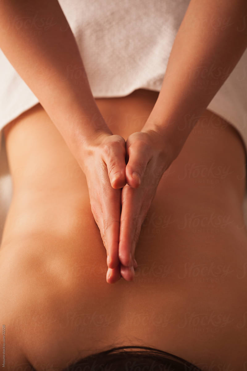 Close up of a masseuse\'s hands massaging female back.