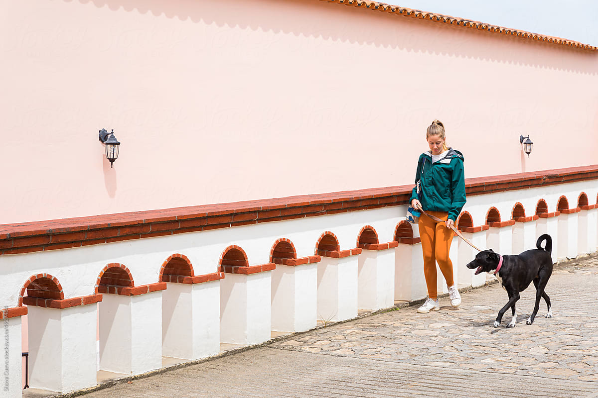 Happy woman in orange pants walking with her black dog