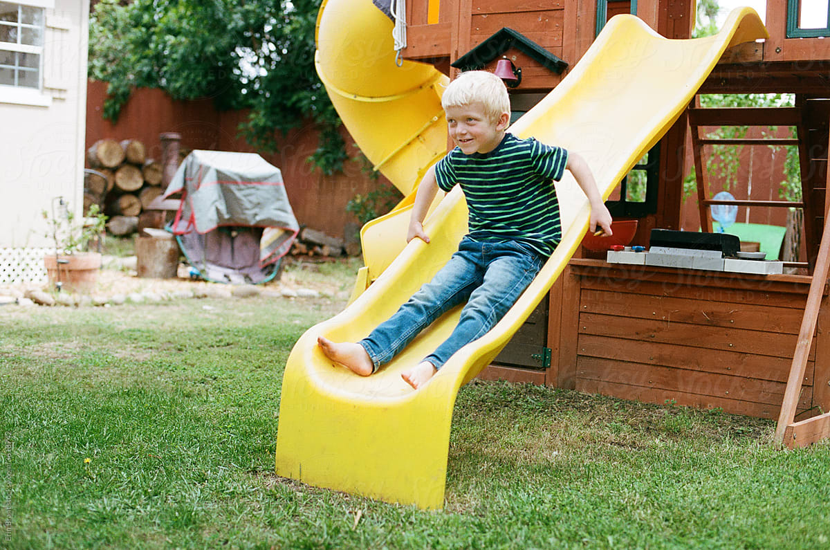 Young boy playing on yellow backyard slide