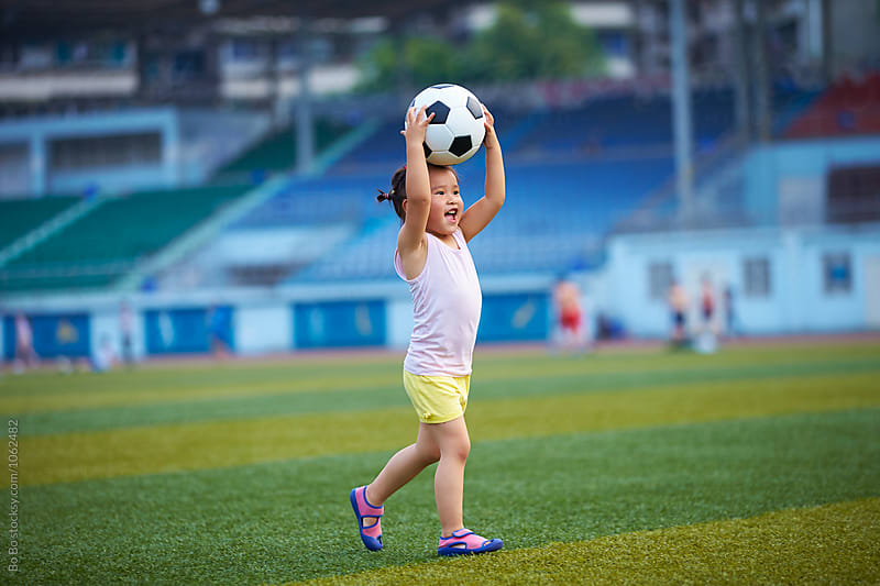 little girl playing football outdoor in the football field
