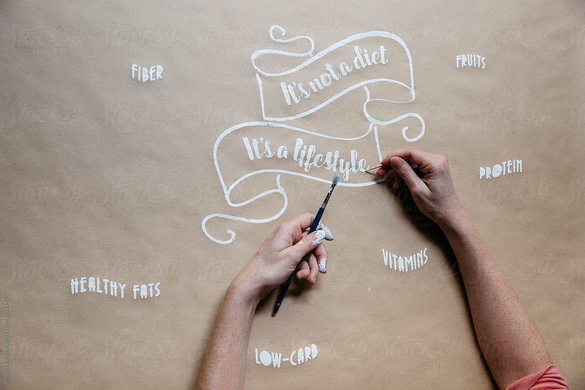 Designer's hands painting a message regarding good health on paper tablecloth