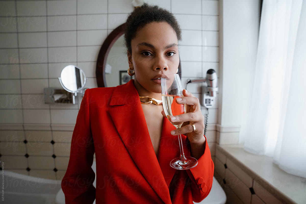 A woman drinks champagne in the bathroom