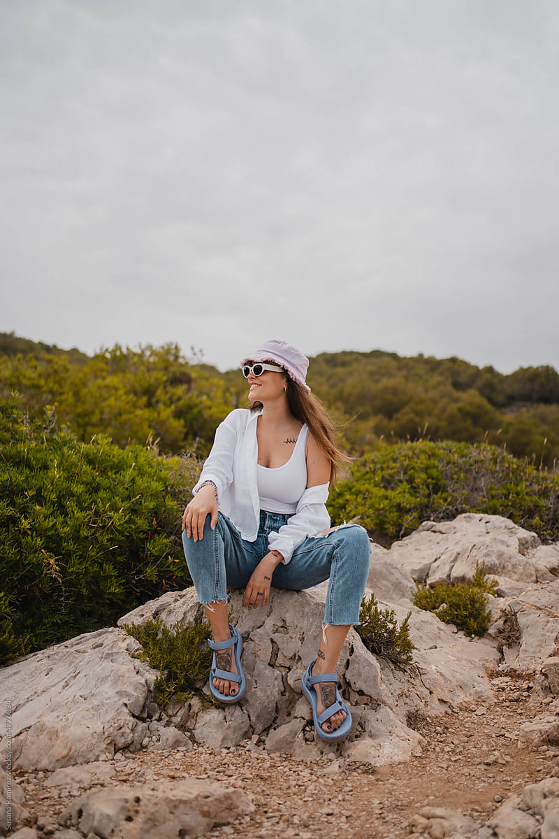 Brunette modern woman sitting on a rock