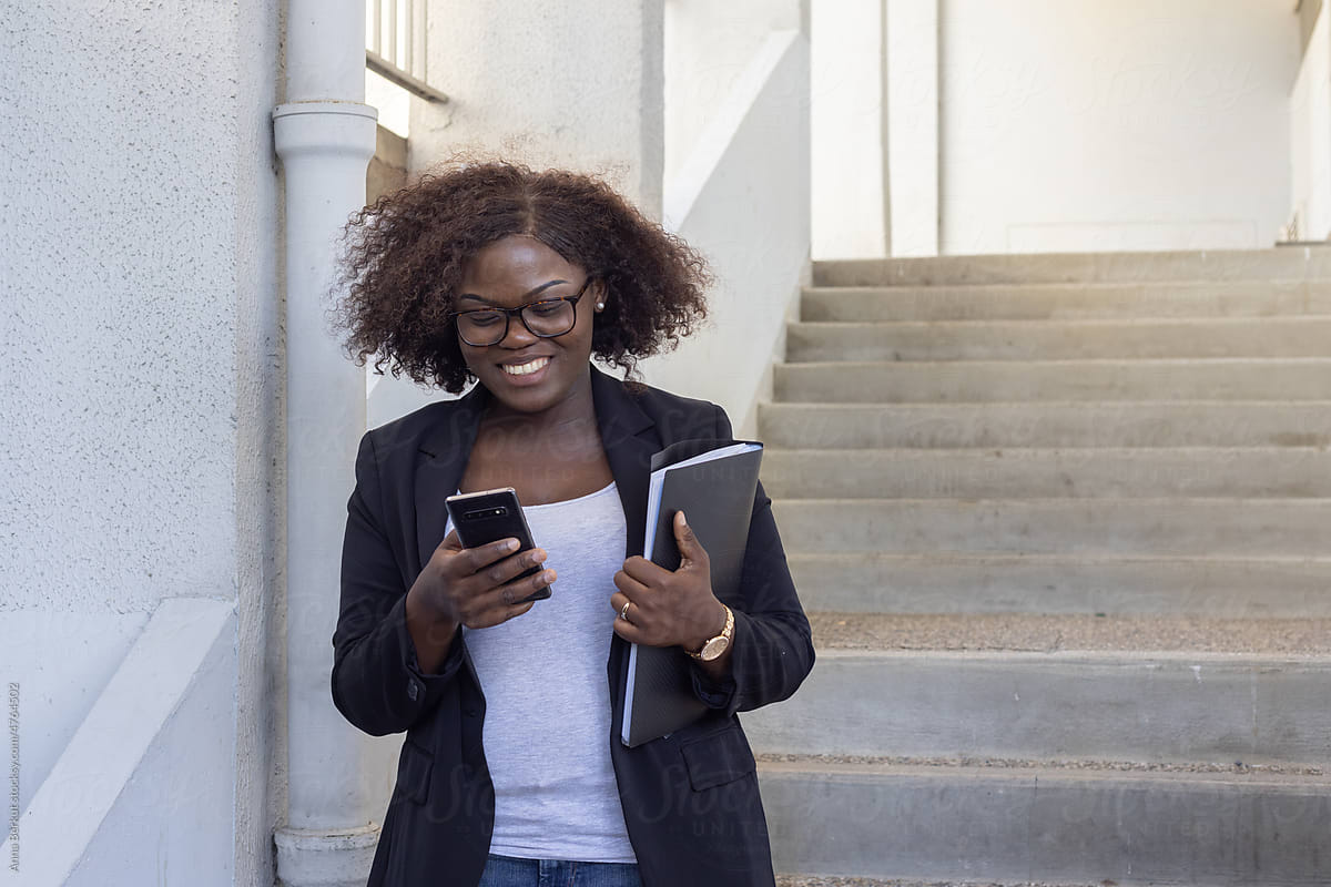 smiling professional woman with smartphone reading email on the go