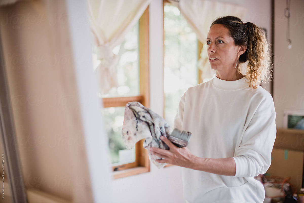 Woman paints a large canvas.