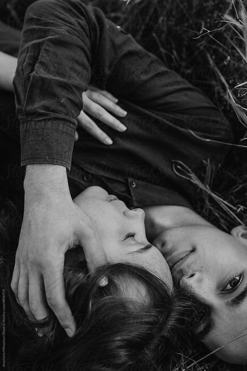 Black and white photo of couple hugging while lying on the ground