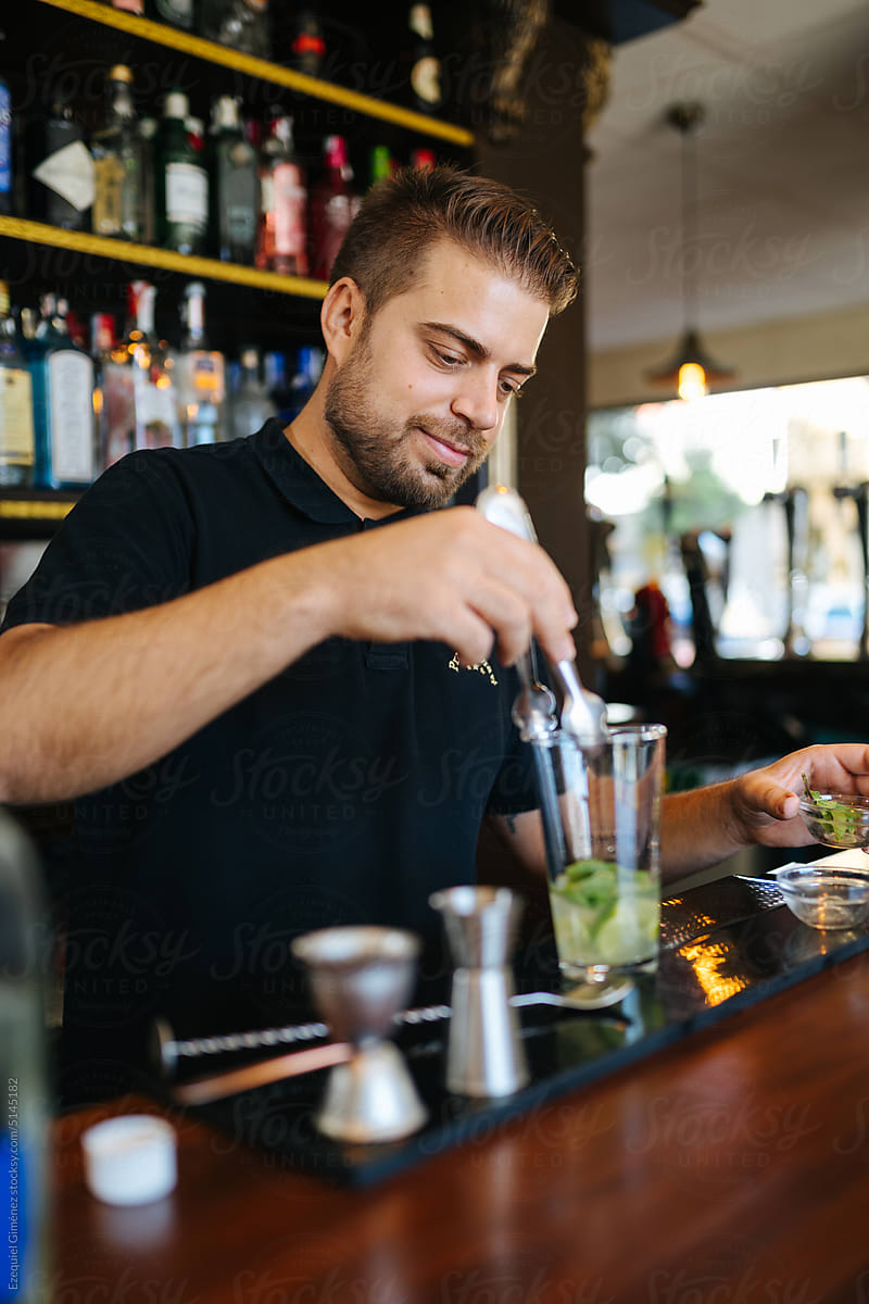 Bearded barman adding ingredients to cocktail