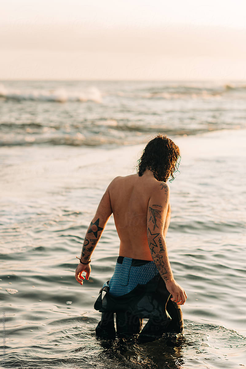 Man with tattoo on his back standing in water