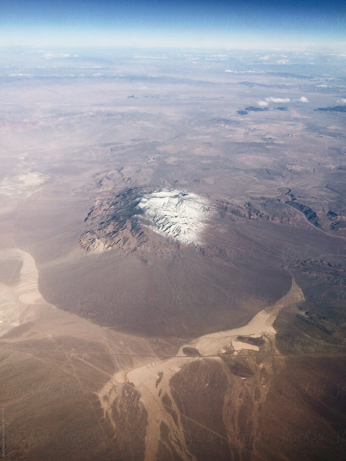View of desert from high above the clouds in an airplane