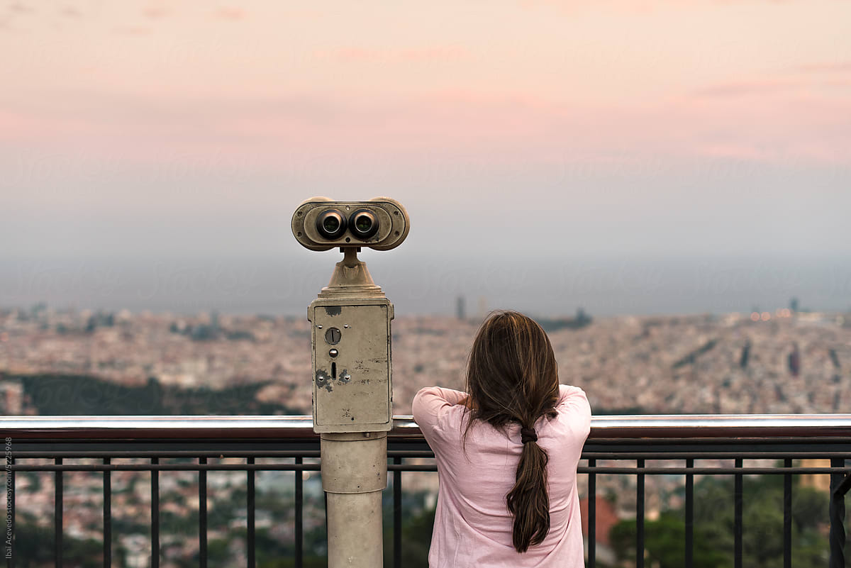 Female kid next to binoculars looking at the city