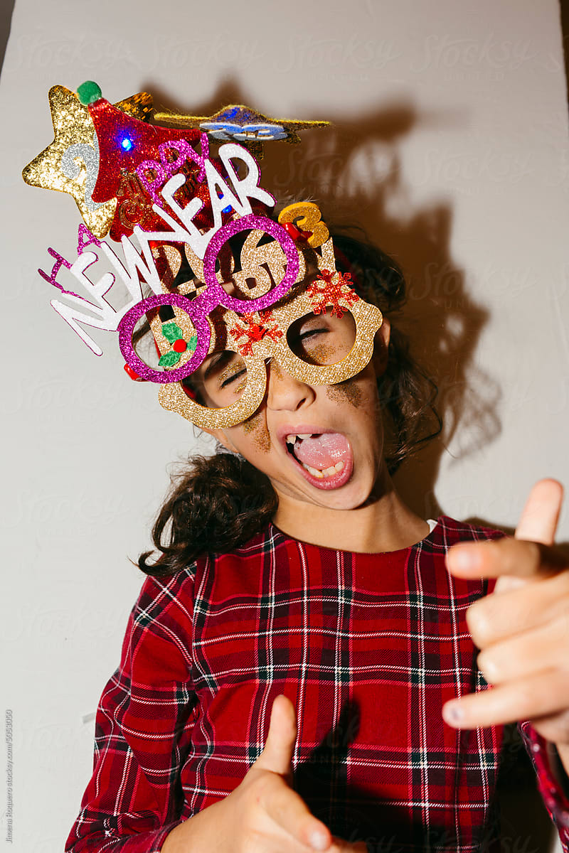Kid making funny faces wearing Happy 2023 glittery party accessories