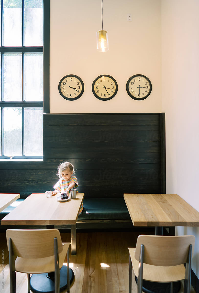 little girl sits alone in a school lunchroom