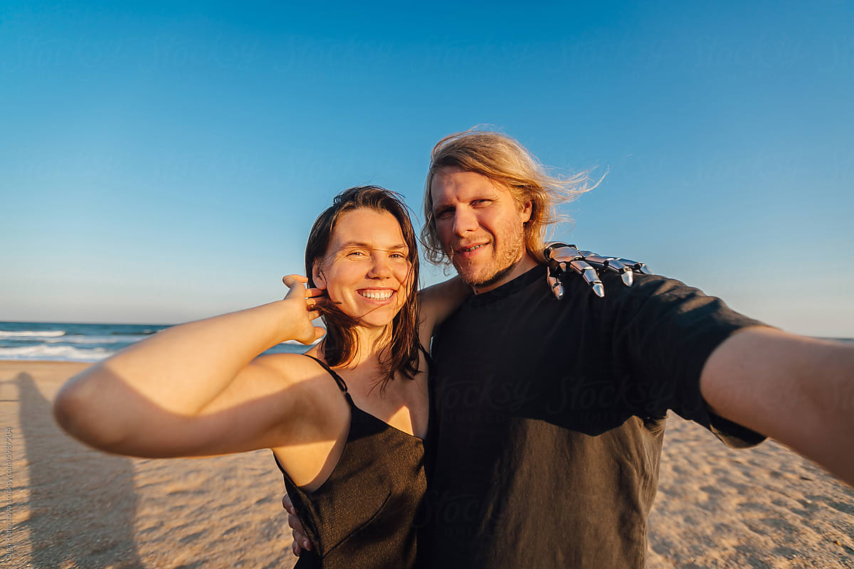 Wide angle selfie of a happy couple at the beach during the sunny day