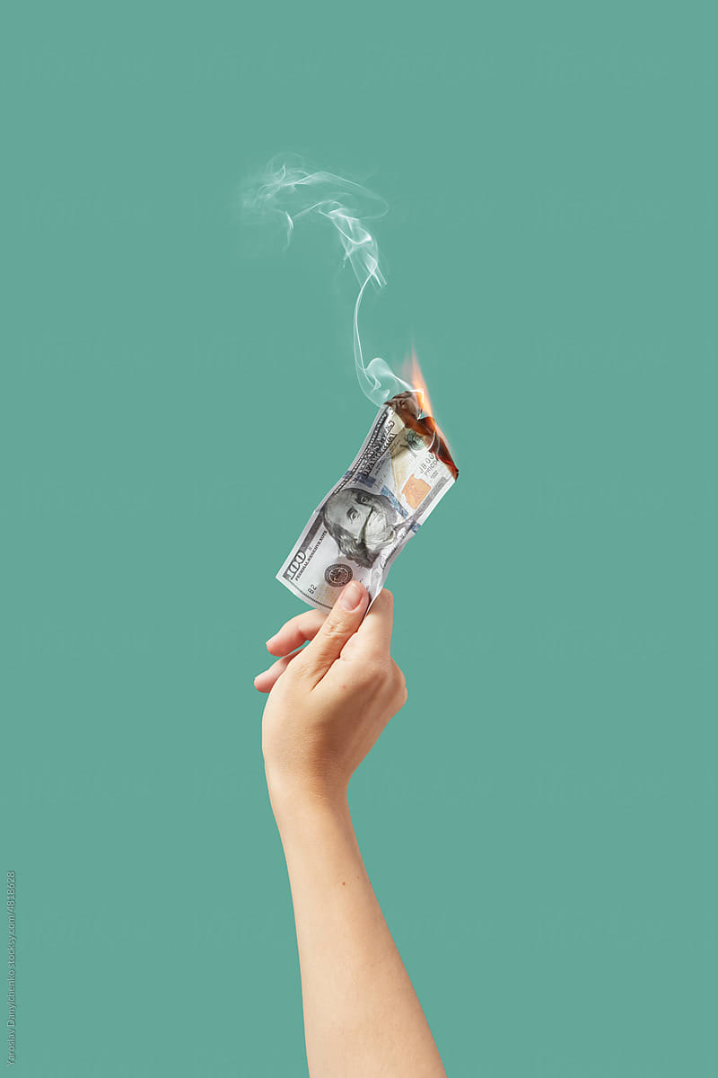 Burning dollar banknote in woman\'s hand.