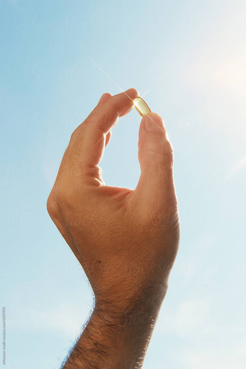 Hand holding D vitamin capsule