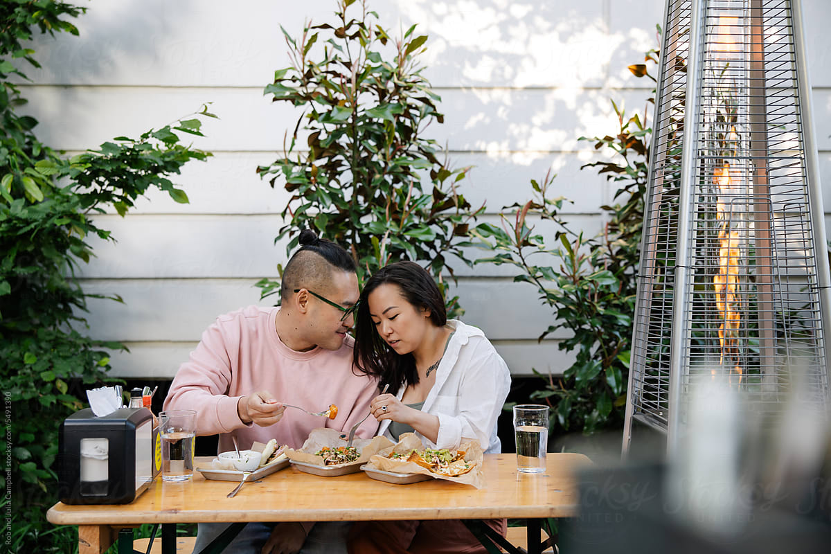 Happy couple connecting and eating tacos together at a restauran