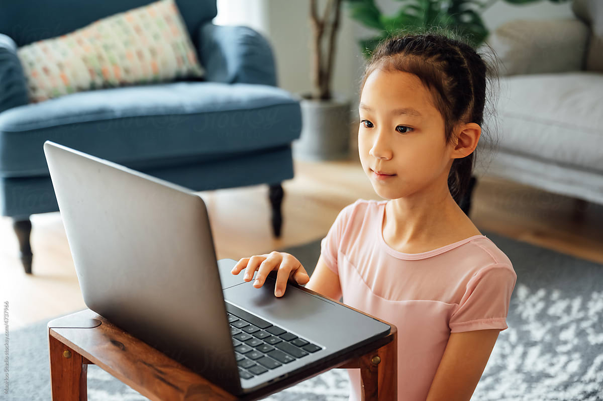 Little girl using laptop attending online tutorial