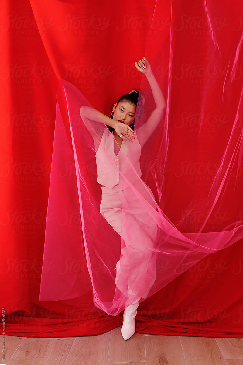 Graceful elegant woman dancing behind red veil