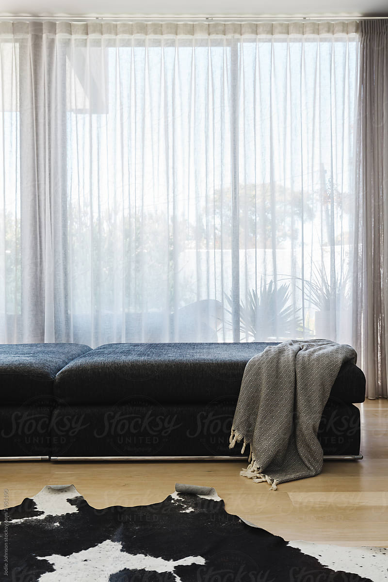 Living room sofa with sheer curtains and cowhide rug