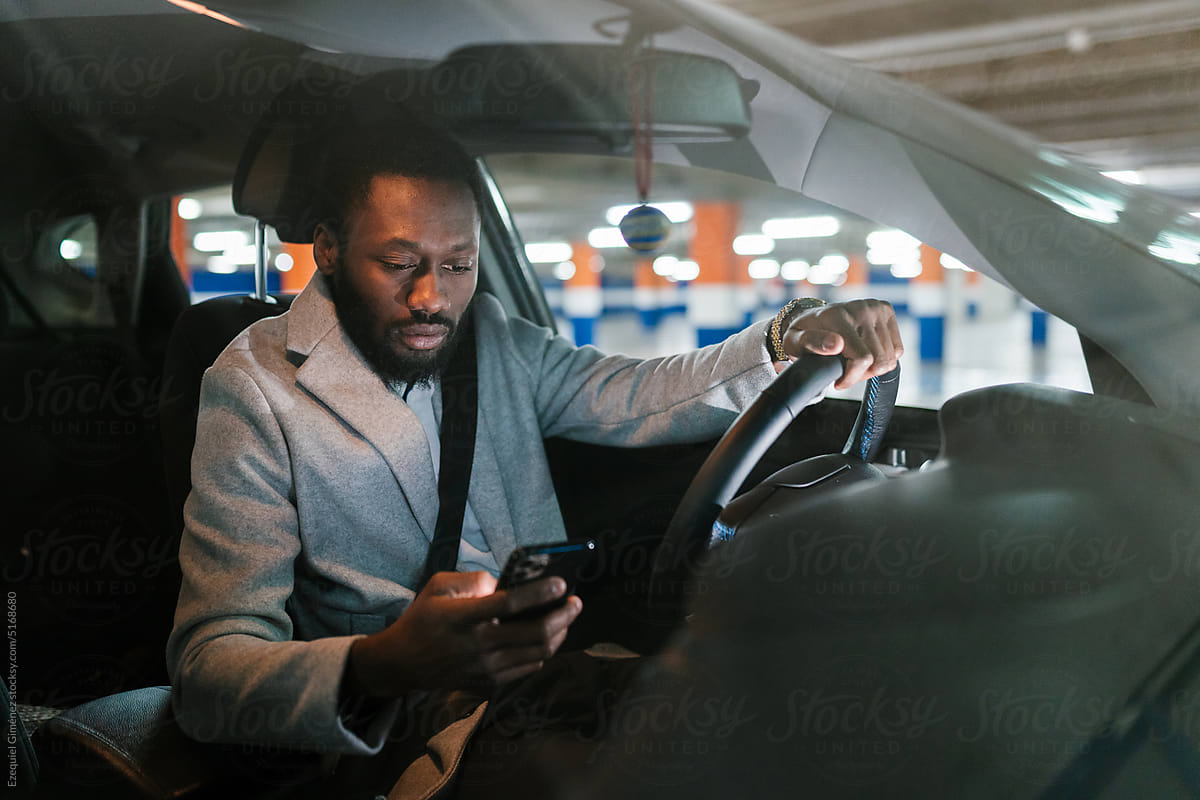 Serious African American man using smartphone in car