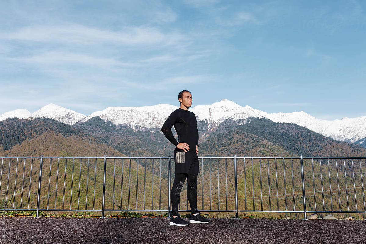 Confident male athlete standing against mountains