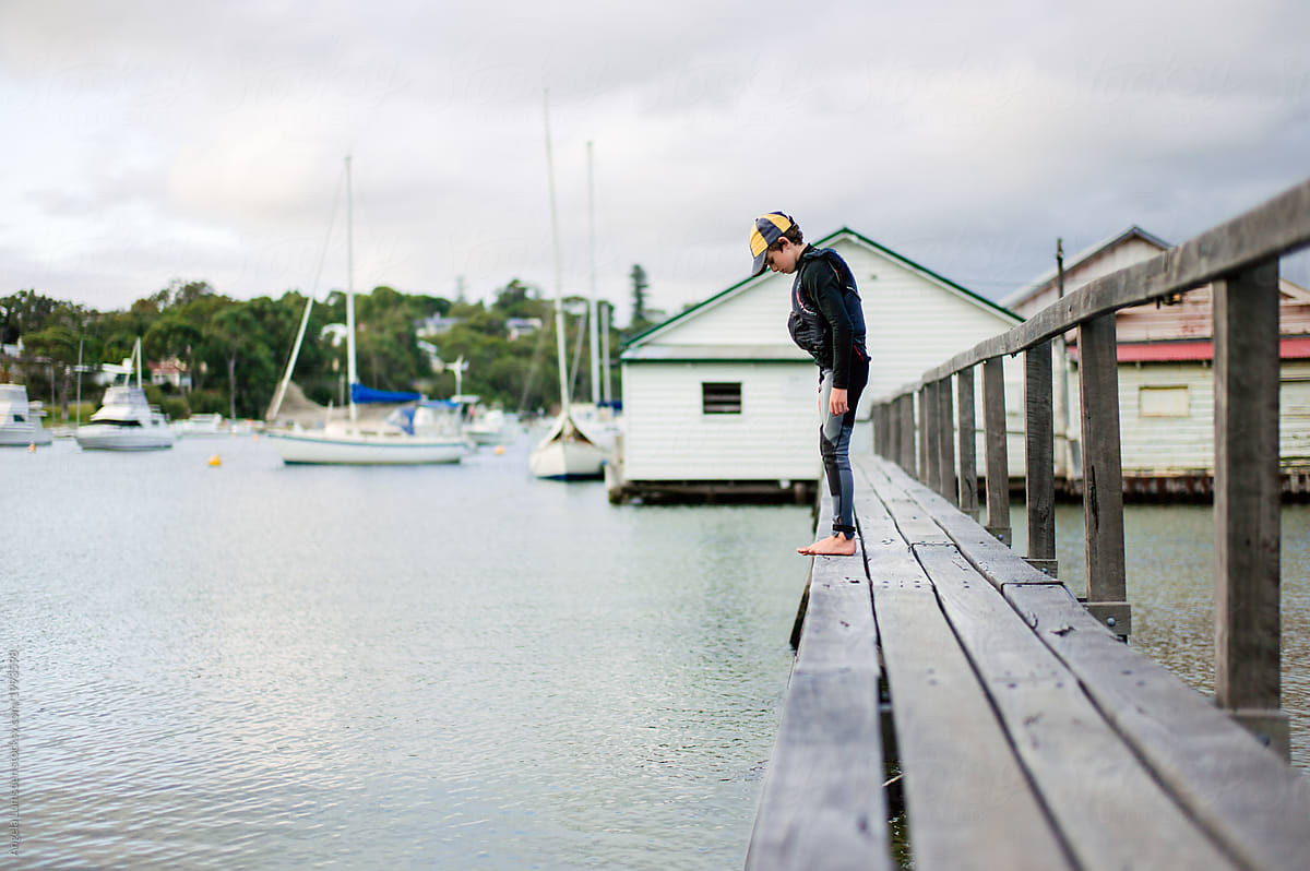 Boy in sailing clothes on a jetty to a boat house