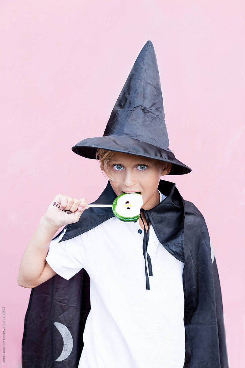 Blonde boy in Halloween costumer eating candy outdoor.