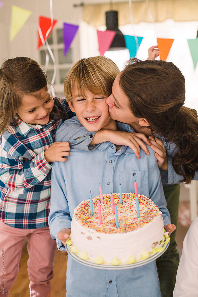 Girls congratulate a birthday to a  boy holding his cake