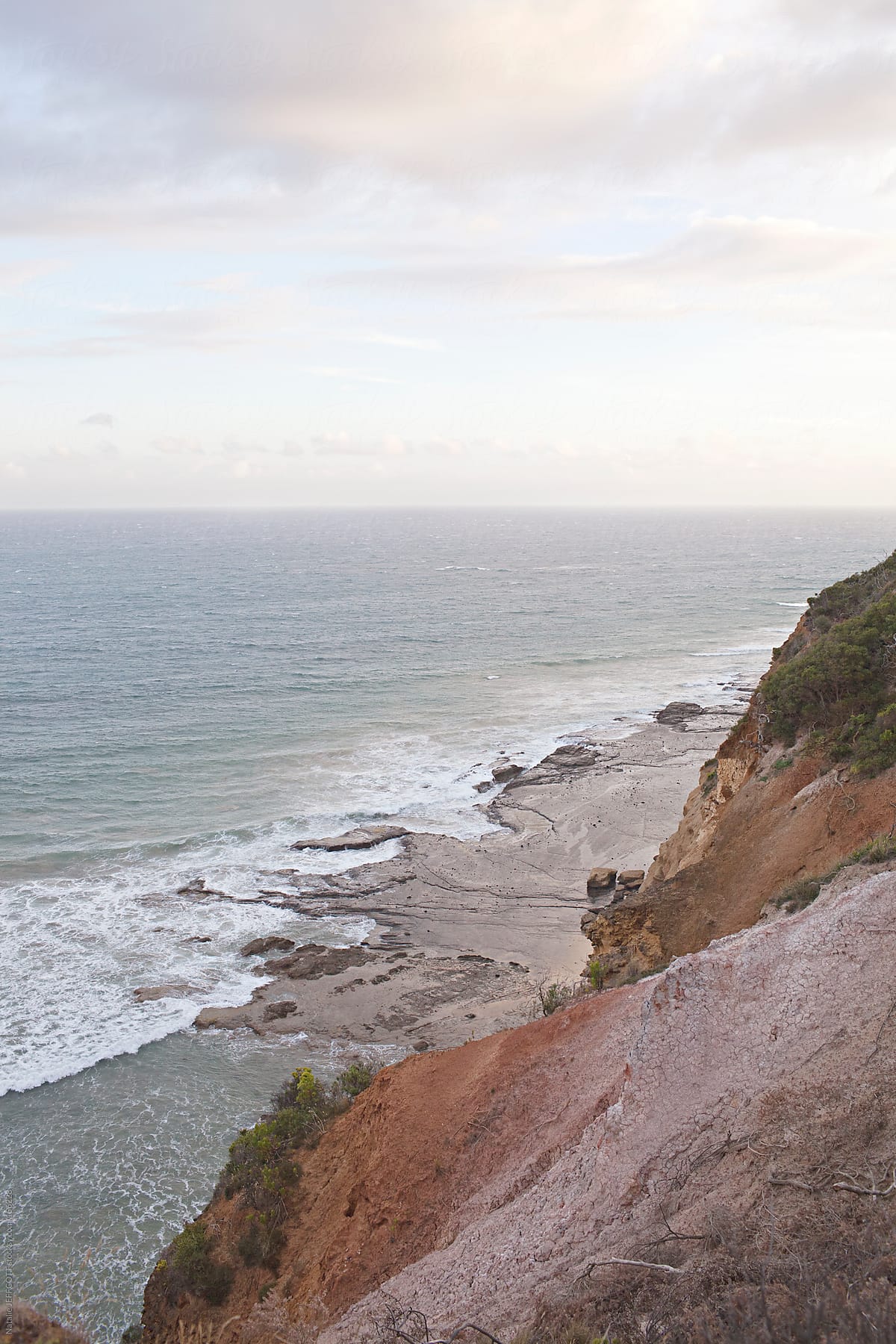 view from top of cliffs looking down at the ocean at sunset