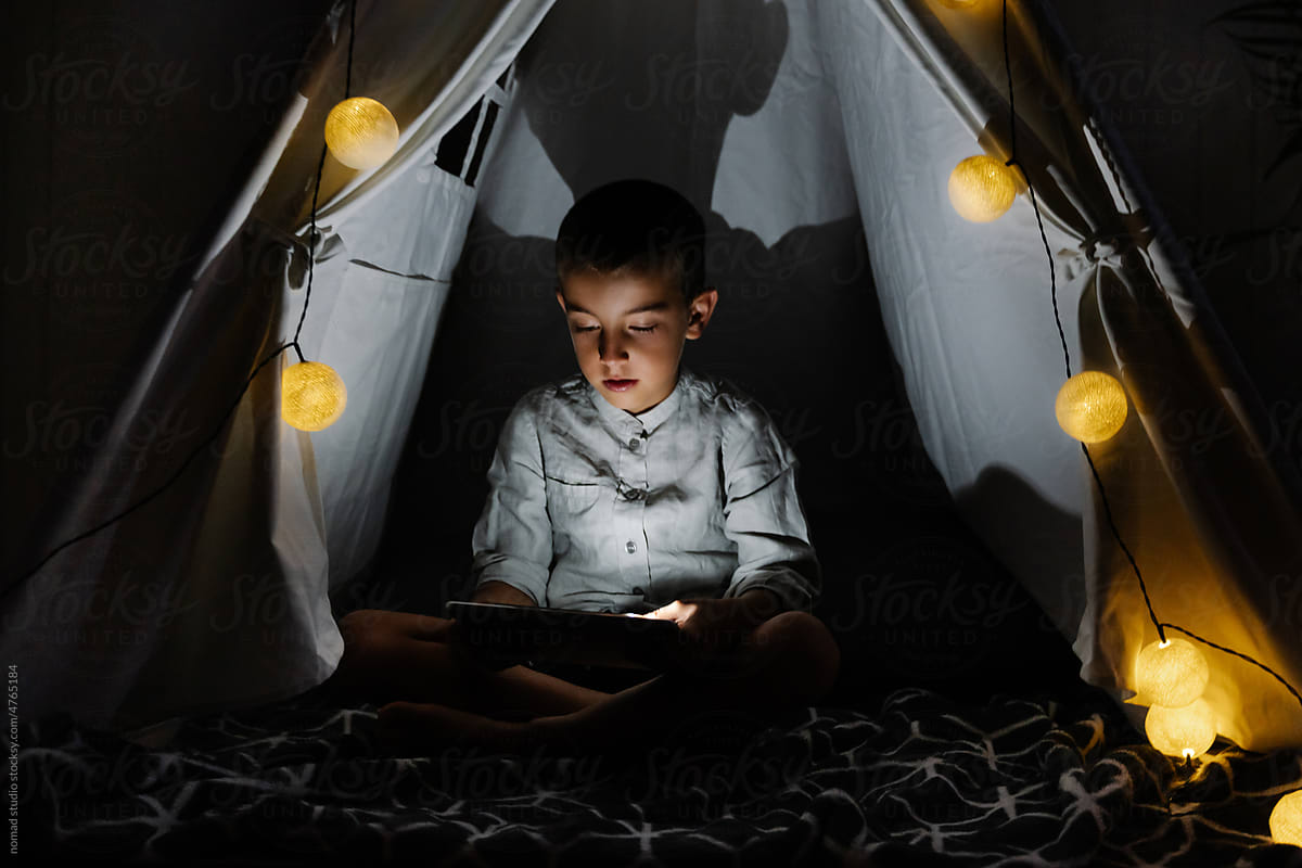boy watching a movie on his tablet in the tent