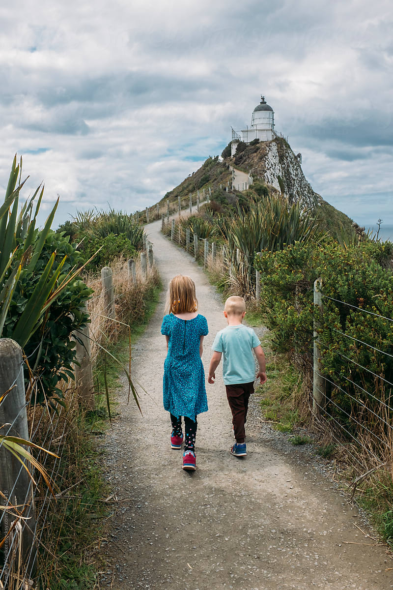 Young children walking towards a lighthouse