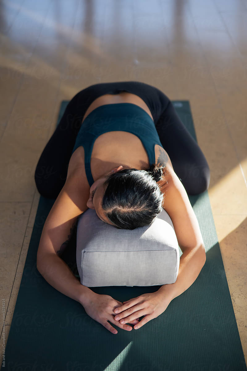 Woman in child\'s pose using yoga pillow.