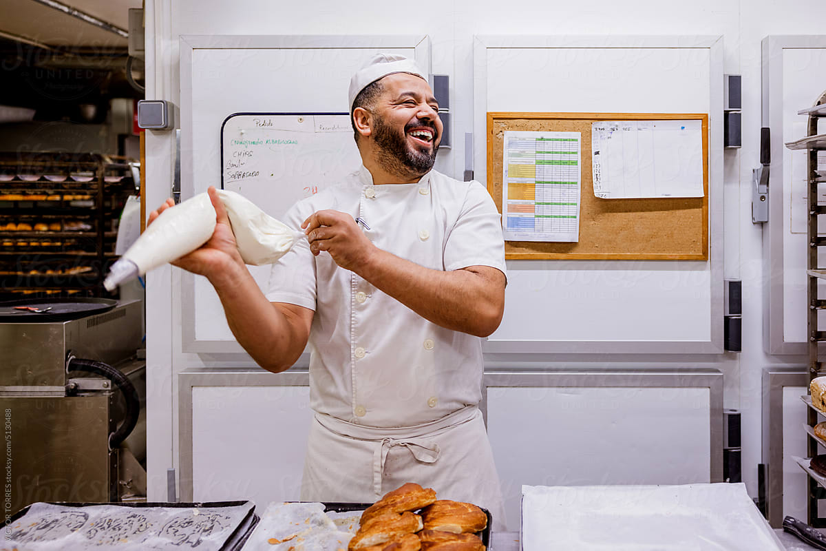 Happy male baker with pastry bag