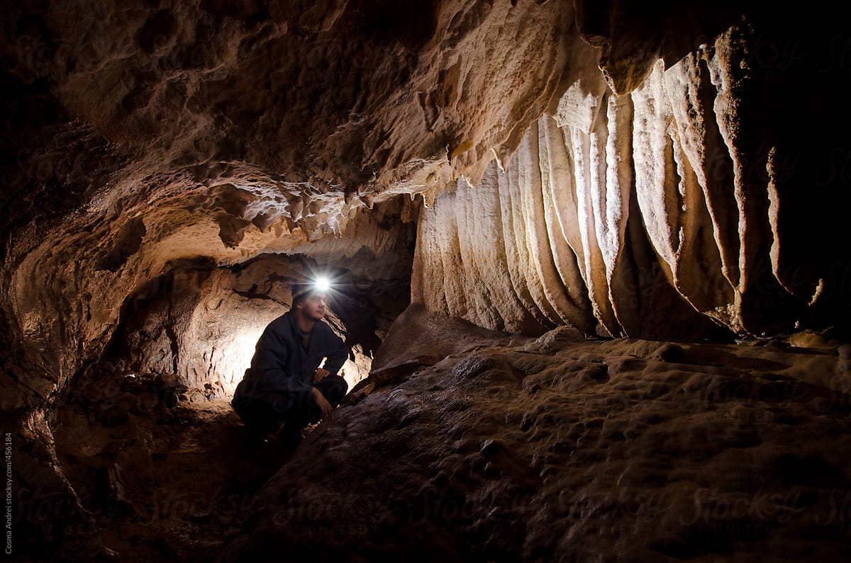 Cave underground with stalactites and speleologist man explorer