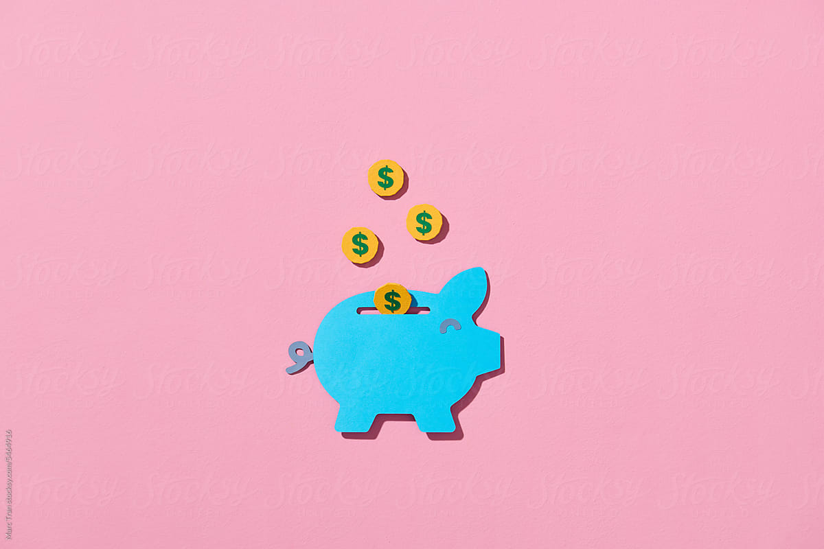 Golden coins falling into a pink piggy bank, isolated on pink