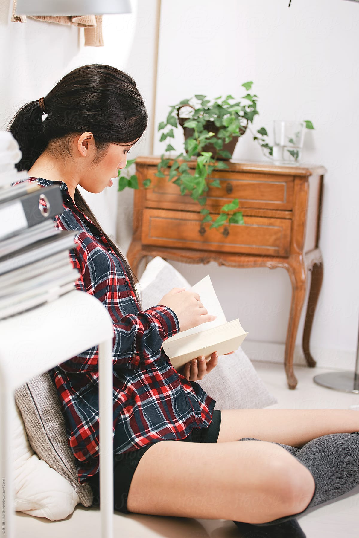 Casual asian woman reading a book in home.