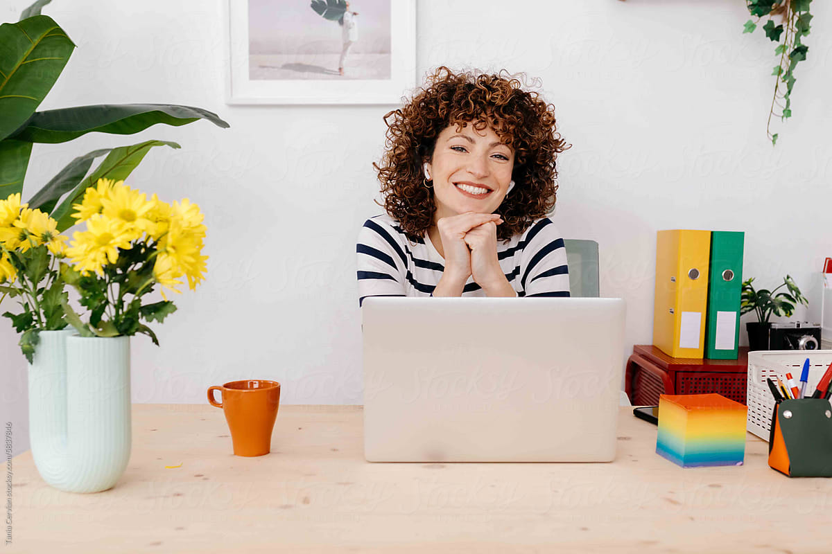 Cheerful woman with hands at chin in office